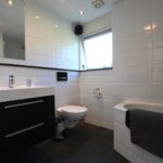 Sandepark 69. Badkamer met douche, ligbad, toilet en badmeubel.