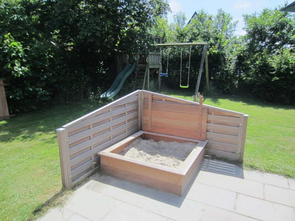 Sandepark 69. Tuin met speeltoestel met schommel en glijbaan. Op de voorgrond een zandbak.