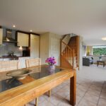 Sandepark 88. Overzichtsfoto woonkamer met vaste trap naar de verdieping, 6 persoons eettafel en keuken. Op de achtergrond de zithoek met bank en 2 stoelen.